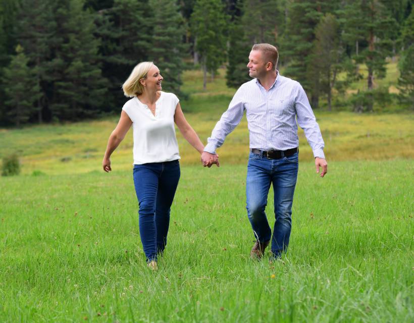 Paar läuft Hand in Hand über eine Wiese